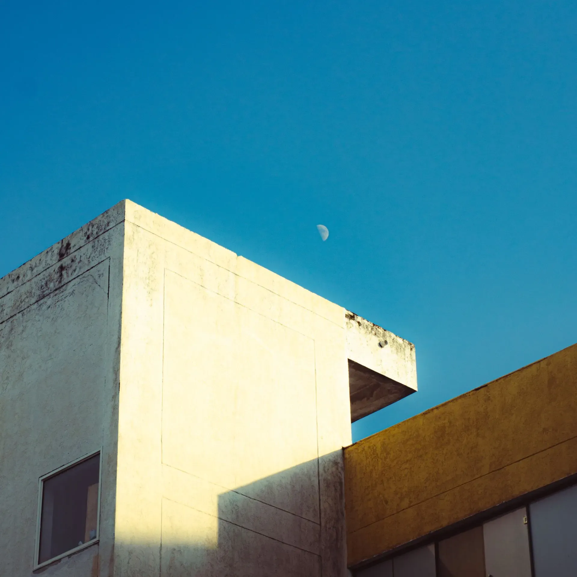 Modern building corner under a vivid blue sky.