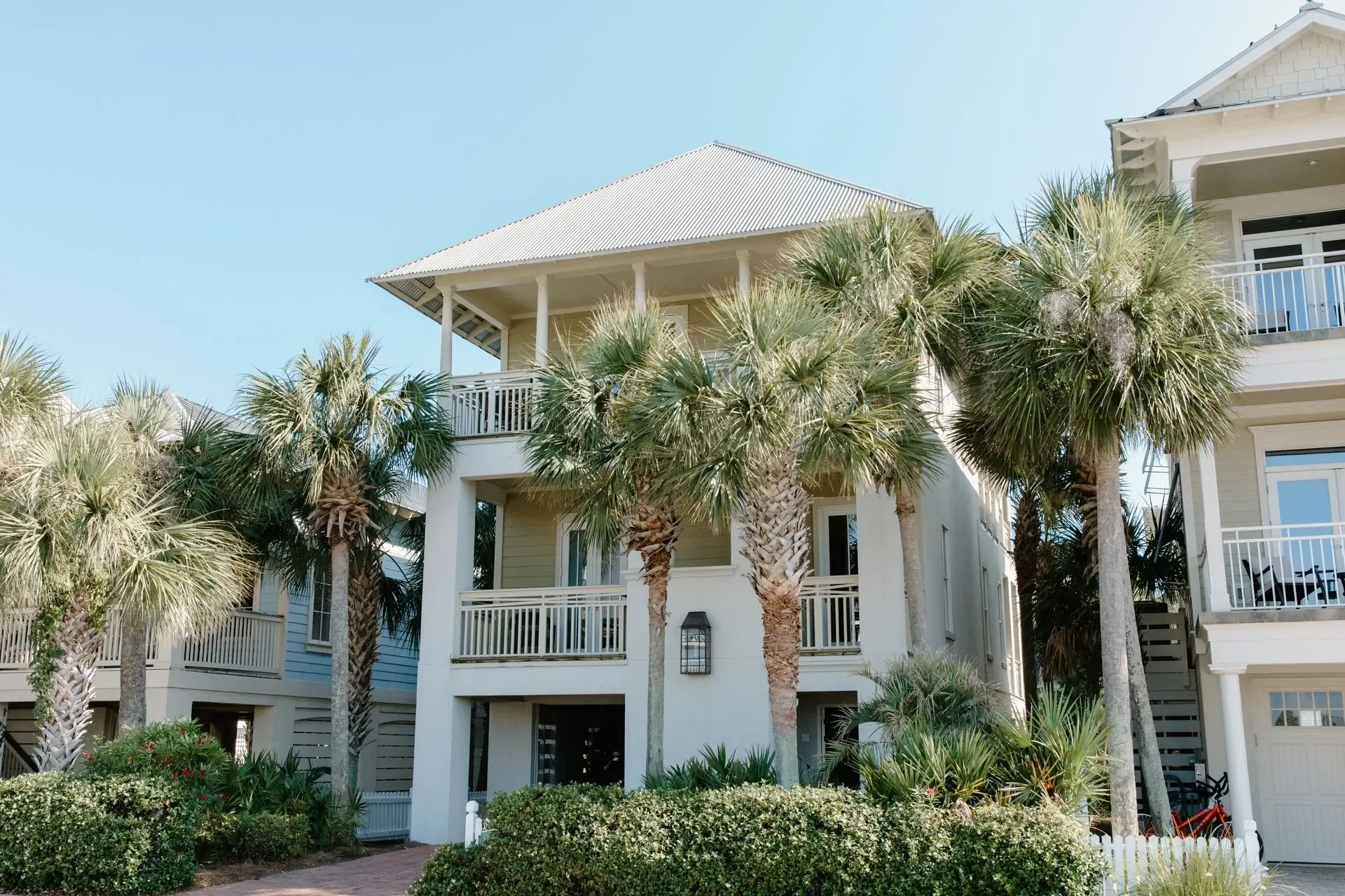 White coastal condo entrance framed by palm trees and landscaping.